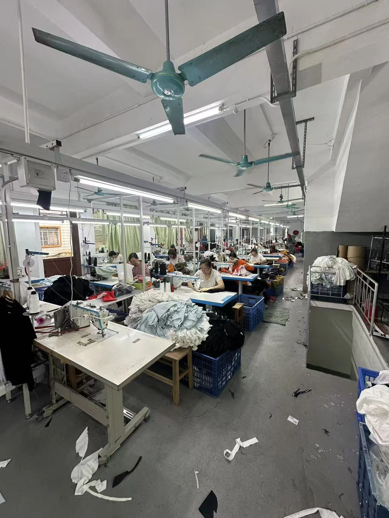 Workers at rows of sewing machines with garments in progress